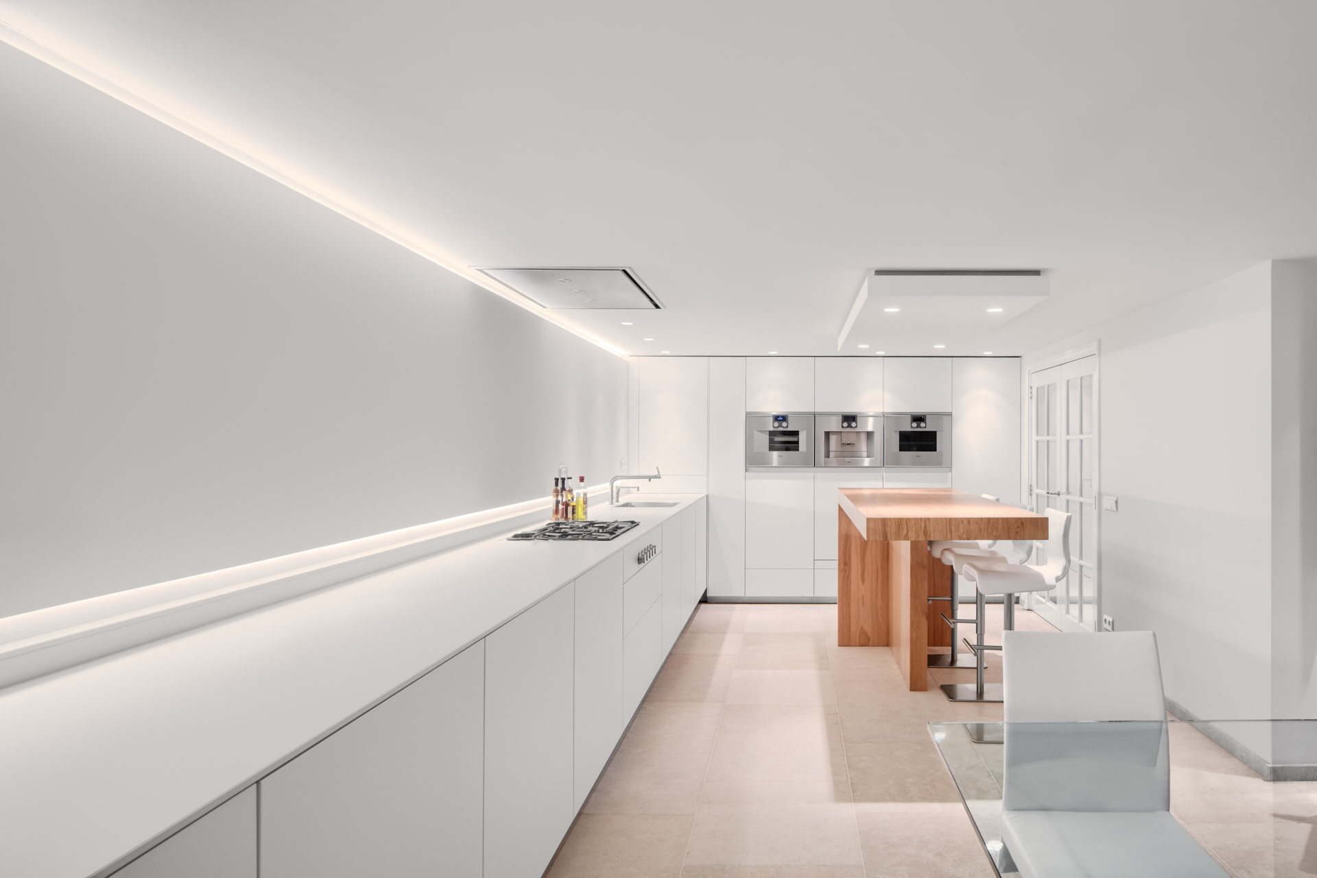 Moderne witte keuken met hout en verlichting ontwerp door binnenhuis architect Maxim Winkelaar.