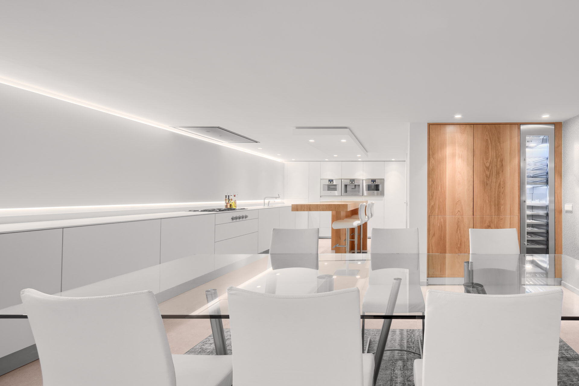 Moderne witte keuken met hout en verlichting ontwerp door binnenhuis architect Maxim Winkelaar.