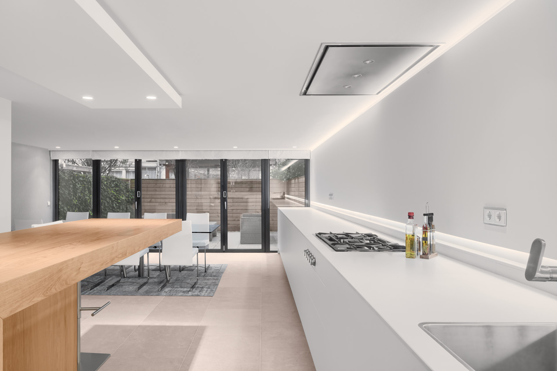 Moderne witte keuken met hout en verlichting ontwerp door binnenhuis architect Maxim Winkelaar.