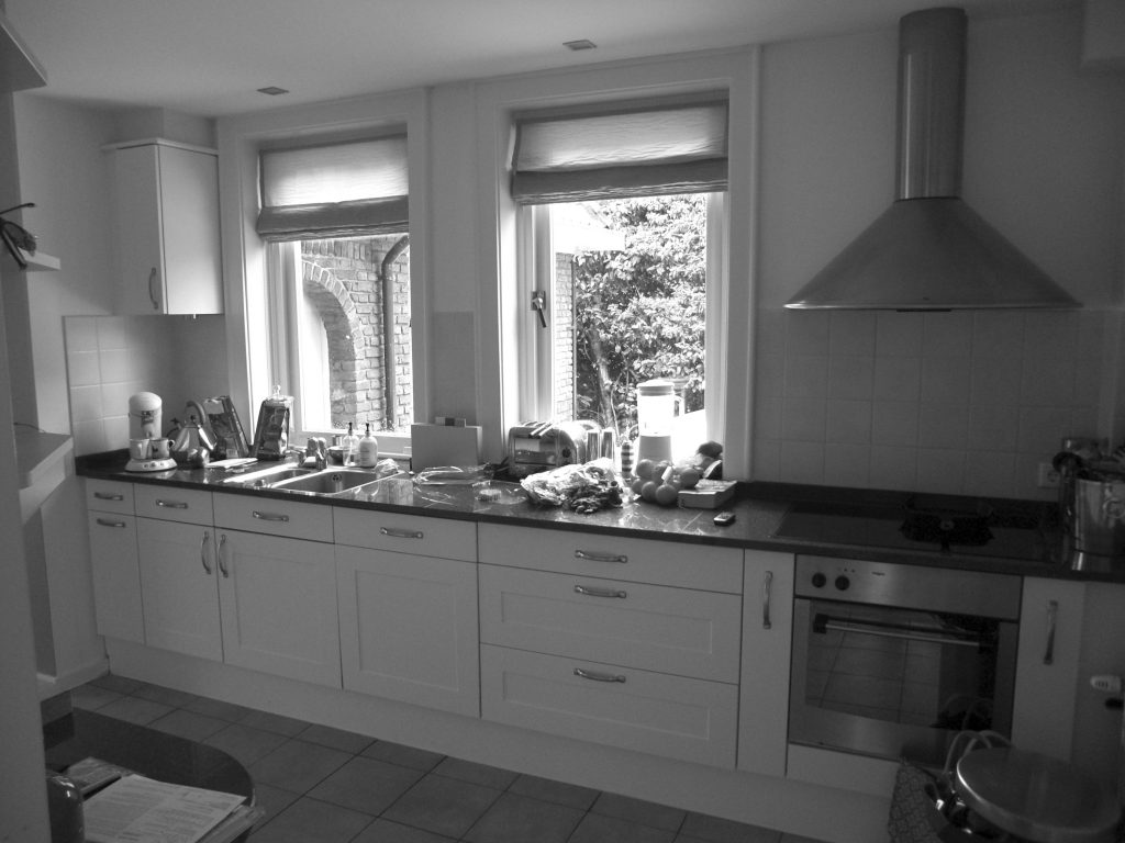 Bouwfoto villa Naarden Wij hebben een nieuw ontwerp gemaakt voor de keuken en bijkeuken met een uitbouw. Om de huidige keukenruimte te betrekken bij de uitbouw hebben wij het aanrecht als verbindende element gemaakt. Het bijna 8 meter lange aanrechtblad is gemaakt van beton en is op locatie (in het werk) gestort en gepolijst. Het betonnen aanrecht bevat geïntegreerd ‘pitt cooking’. De kasten van de keuken zijn gemaakt van licht eiken. Het aanrechtblad loopt over naar een bargedeelte. Bij het bargedeelte zit in het betonnen aanrecht plaatselijk een elektrische ‘vloerverwarming’, op deze manier is de ‘kou eraf’ als men aan de bar zit. Boven het bargedeelte is het dak plaatselijk verhoogd met daarin ramen rondom. Door deze ramen komt een mooie natuurlijke lichtinval in het eetgedeelte.